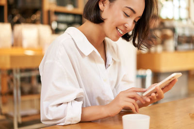 Young woman using mobile phone in cafe