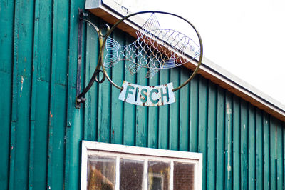 Low angle view of metallic fish sign on wall in city