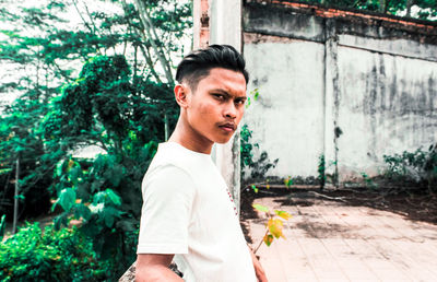 Portrait of young man standing against plants