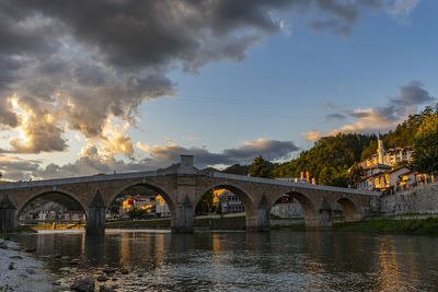 Arch bridge over river against sky