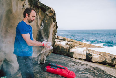 Man rubbing powder with hands while standing at beach