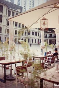 Man listening to music while sitting on chair at cafe in city