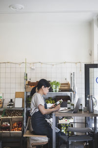 Female employee writing while holding bottle in store