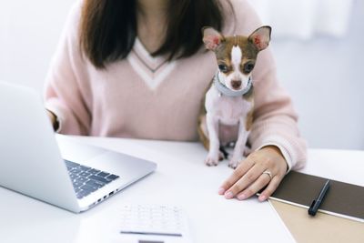 Midsection of woman using mobile phone while sitting on table