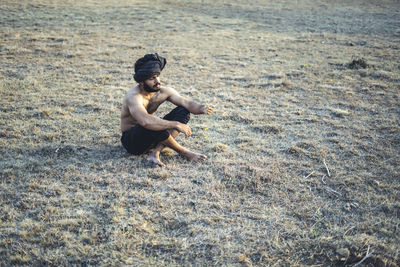 Young indian farmer standing on a wasteland field. crops not growing due to shortage of rain