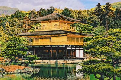 Built structure by lake and trees against sky