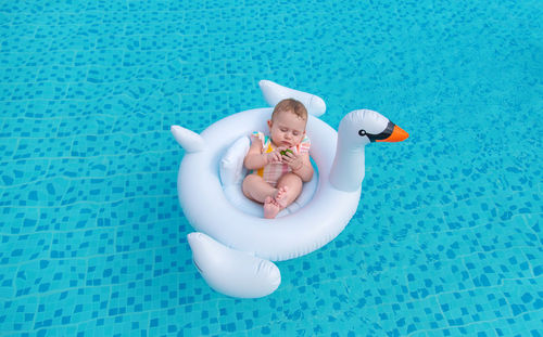 Cute baby girl sitting on inflatable ring in swimming pool