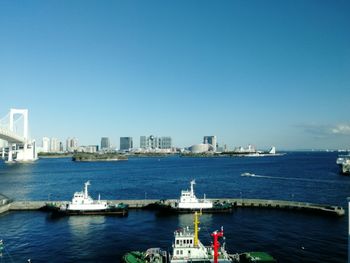 Scenic view of sea by buildings against clear blue sky