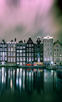 Buildings by river against sky in city