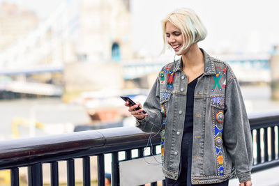 Smiling woman using phone while standing outdoors