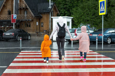 Rear view of people walking on road in city