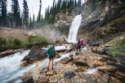 Backpackers admire laughing falls waterfall in yoho national park