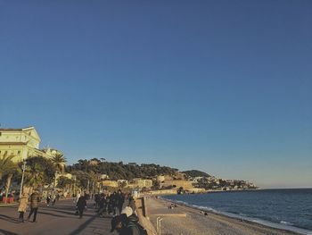 Illuminated city by sea against clear sky