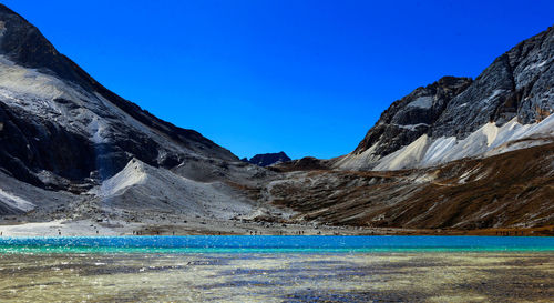 Scenic view of lake and mountains against clear blue sky