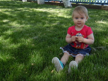 Portrait of girl sitting on grassy field