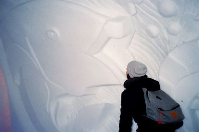 Rear view of young man with backpack standing by snow