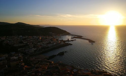 High angle view of sea and buildings against sky during sunset