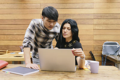 Young woman using mobile phone while sitting on table