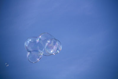 Low angle view of bubbles against blue sky