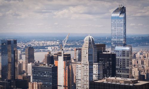 Modern cityscape by sea against sky