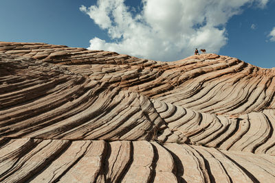 Hiker and her dog sit atop ridge on a petrified sand dune utah desert