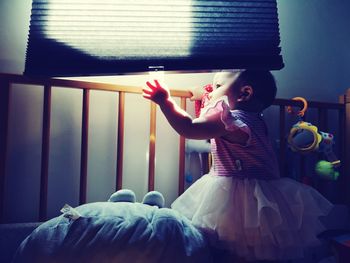 Cute girl in crib by window at home