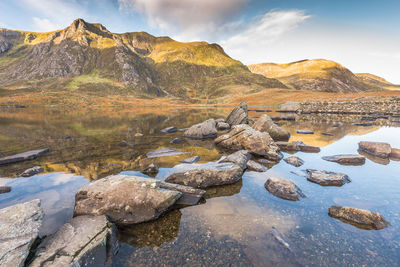 Rocks by lake against sky