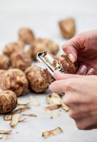 Cropped hands of woman peeling vegetable on marble