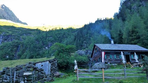 House amidst trees and mountains against sky