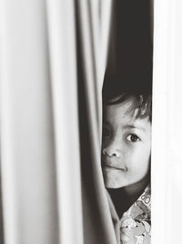 Portrait of cute boy peeking through window