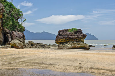 Rock formation on beach against sky