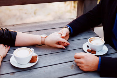 Cropped hands of couple having coffee at table