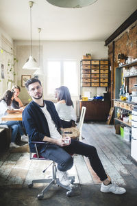 Portrait of confident young male it expert sitting on chair in creative office