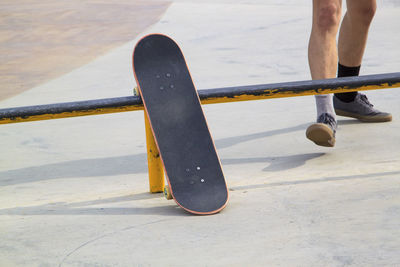 Low section of man with skateboard on footpath