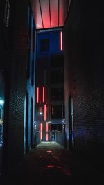 Empty alley amidst buildings at night