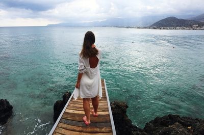 Rear view of woman looking at sea against sky