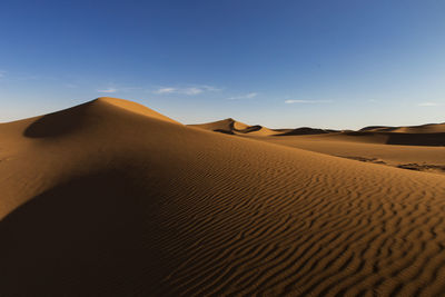 Sand dunes in desert against sky