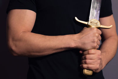 Midsection of man holding hands against black background