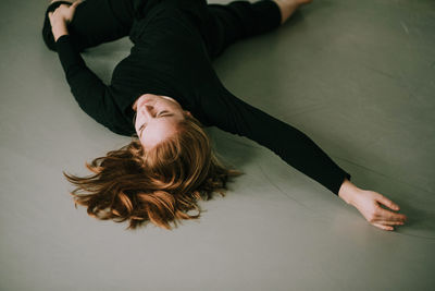 High angle view of woman dancing while lying on floor at home