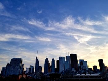 Modern buildings in city against sky during sunset