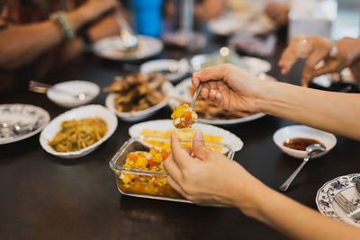 Cropped hand of woman having food at restaurant