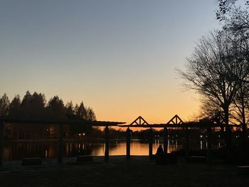 Silhouette bridge over river against sky during sunset