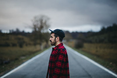 Young man standing on road against sky