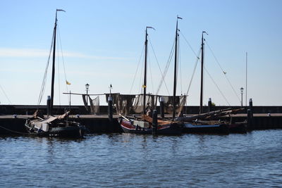 Boats moored at harbor against sky