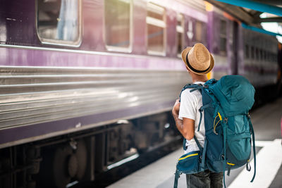 Rear view of man standing by train at railroad station