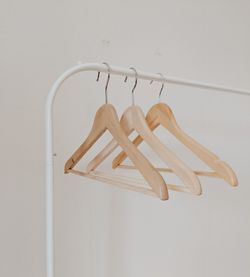 Close-up of coathangers hanging on rod against white wall