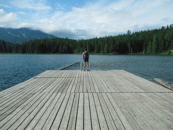 Rear view of man standing by lake against sky