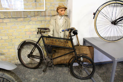 Full length of a man holding bicycle parked against wall