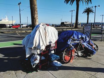 Homeless cart, bicycles and tent on the embarcadero with cars passing by.