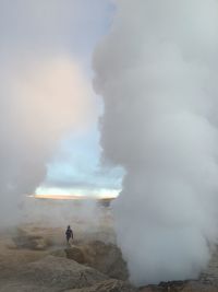 Rear view of man on landscape against cloudy sky